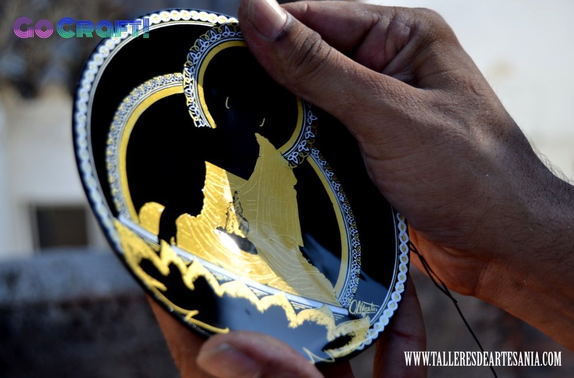 Taller de damasquinado en Toledo. Unas manos limpian un plato de damasquinado recien pavonado.